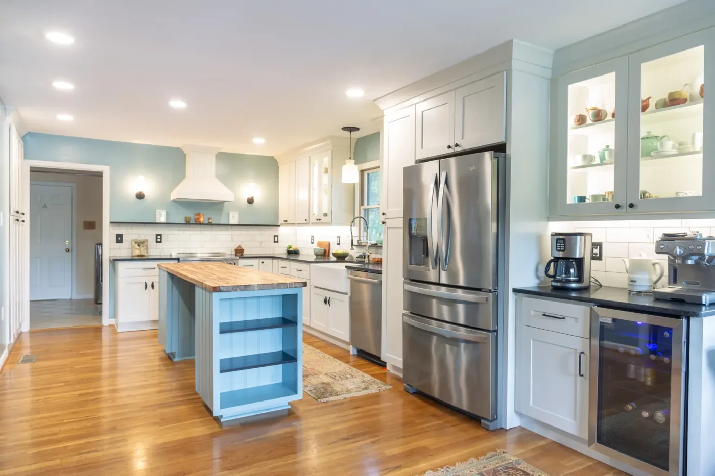 Atlas kitchen renovation with white cabinetry, a blue island, and a wood countertop